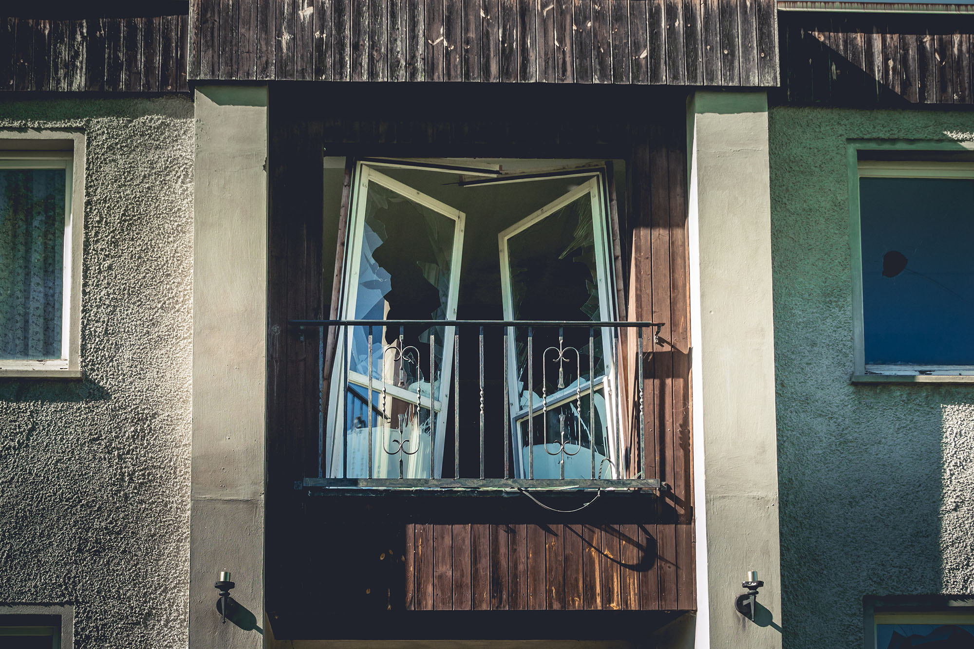 an old abandoned house with balcony and broken windows